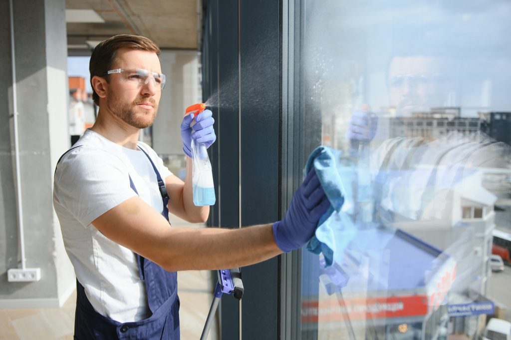 An employee of a professional cleaning service washes the glass of the windows of the building.